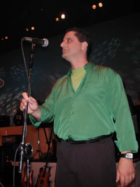 Vocalista masculino com camisa verde no microfone