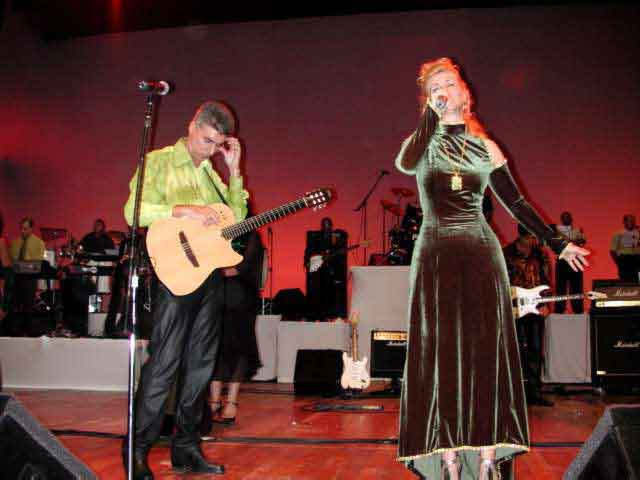 Violonista e cantora de vestido verde performando no palco