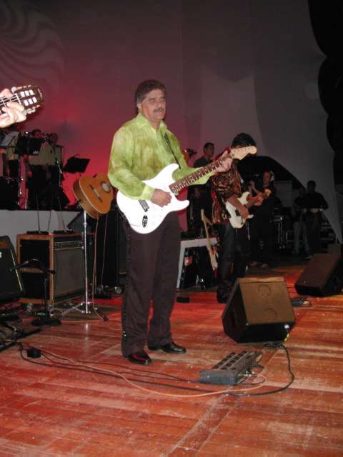Guitarrista de camisa verde tocando guitarra Stratocaster branca