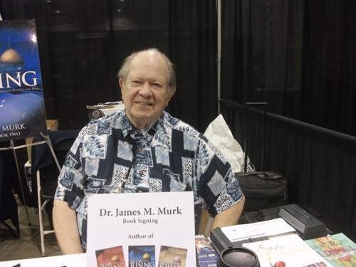 Dr. James M. Murk sentado em sua mesa de autógrafos